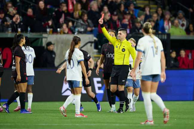 A referee shows a red card to a soccer player on a field