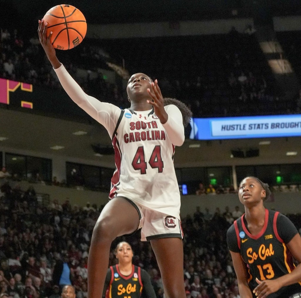 South Carolina guard Agot Makeer shoots a layup. The ball is still in her hands with two USC defenders behind her.