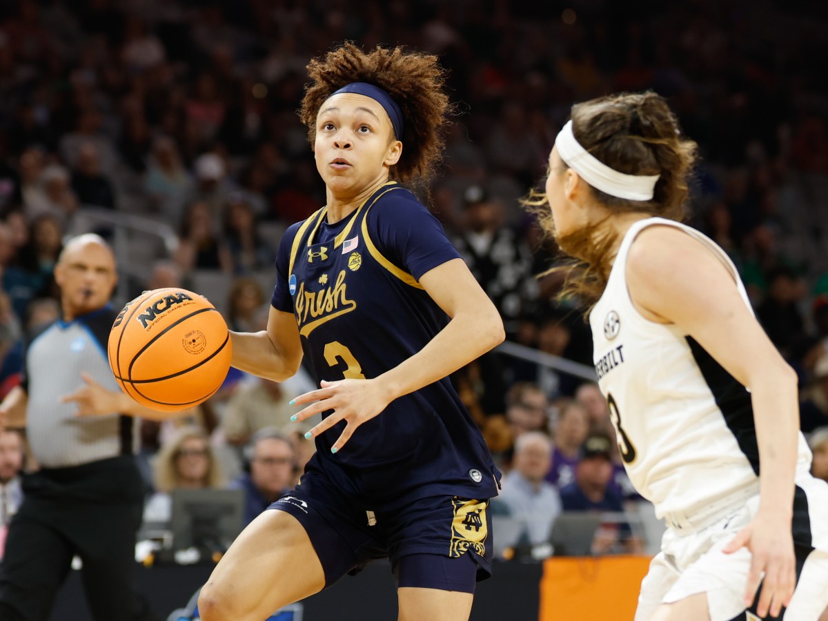 Notre Dame guard Hannah Hidalgo looks up at the basket as she dribbles the ball with her right hand. Vanderbilt guard Aubrey Galvan is on her left, defending her closely.