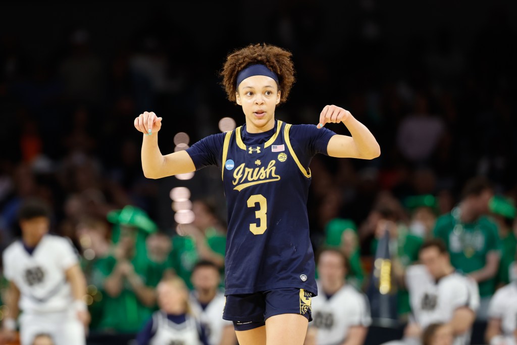 Notre Dame guard Hannah Hidalgo holds both hands up at about shoulder level and points downward.