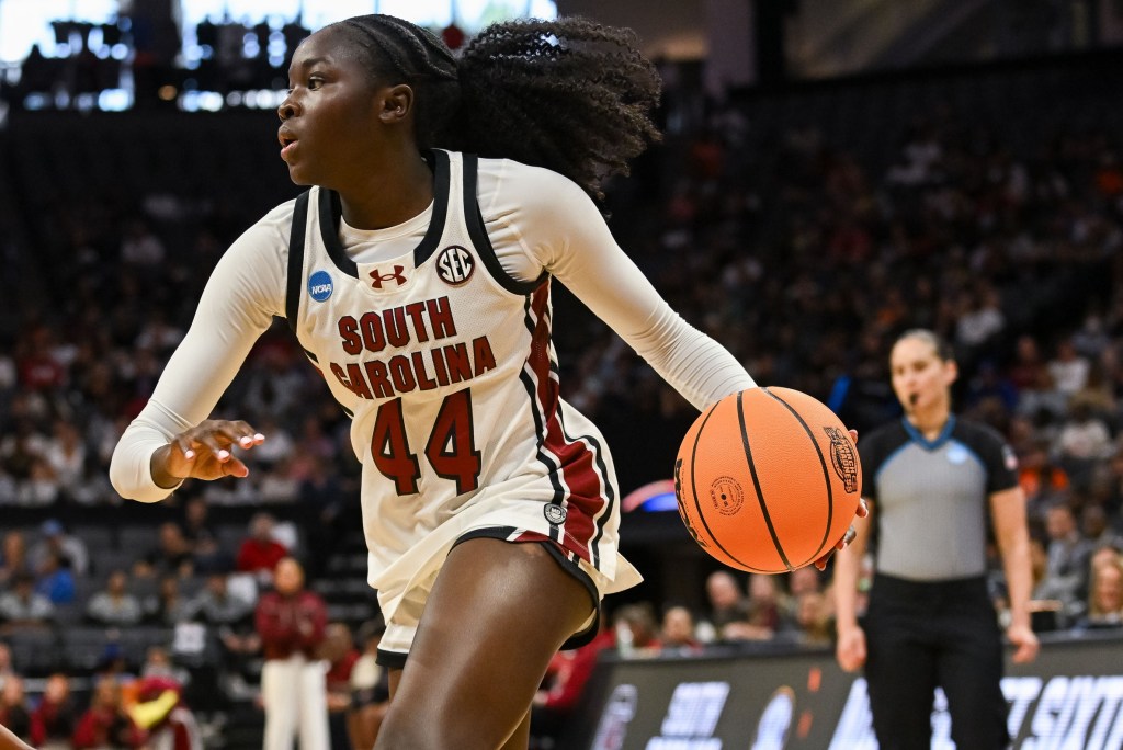 South Carolina guard Agot Makeer drives the ball. The ball is in her hand with a referee standing behind her.
