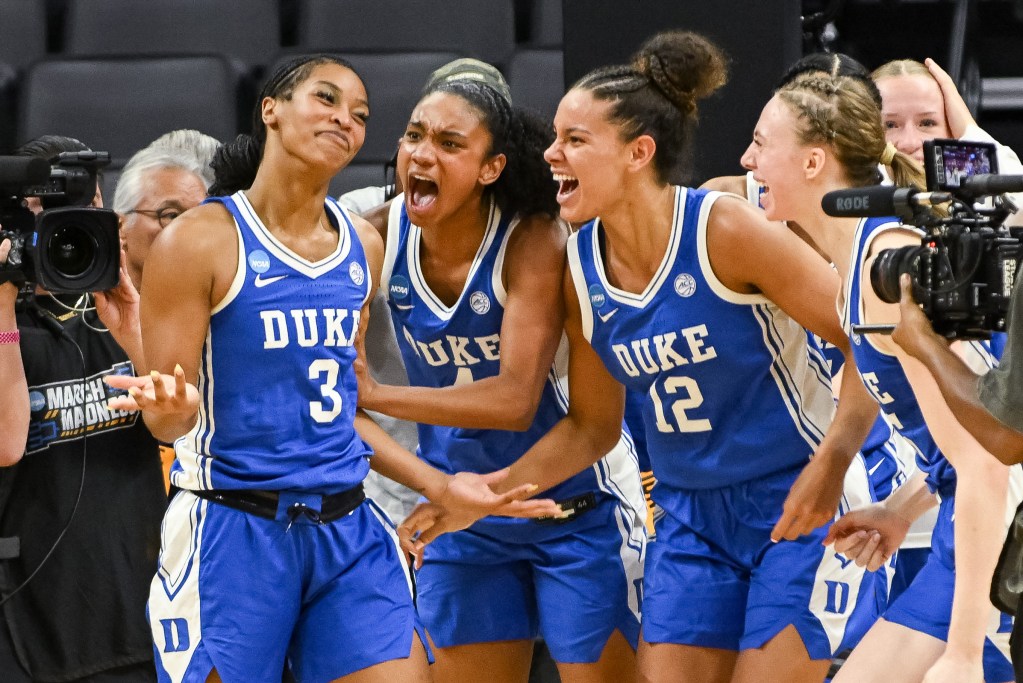 Duke guard Ashlon Jackson shrugs her shoulders and grins after making a game-winning shot. To the right, teammates Riley Nelson, Delaney Thomas and Toby Fournier are screaming in celebration.