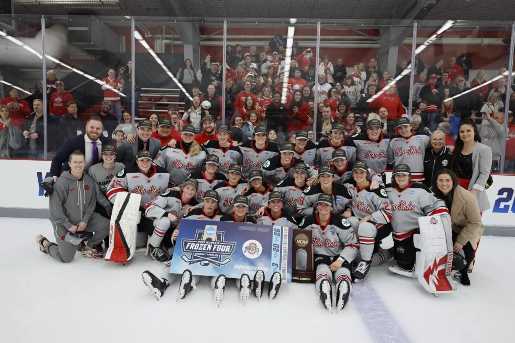 An ice hockey team poses on the ice after winning a big game and clinching a spot in the Frozen Four