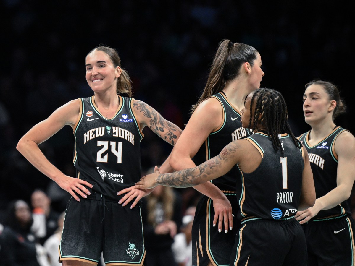 Three New York Liberty players stand together on a court, with their hands on their hips.