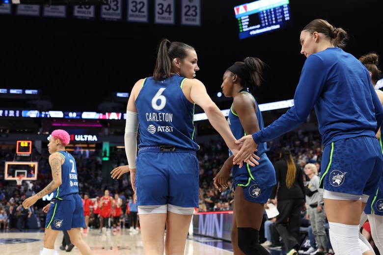 Bridget Carleton in her blue uniform, looks back and greets Maria Kliundikova. Natisha Hiedeman is in the background with her pink hair.