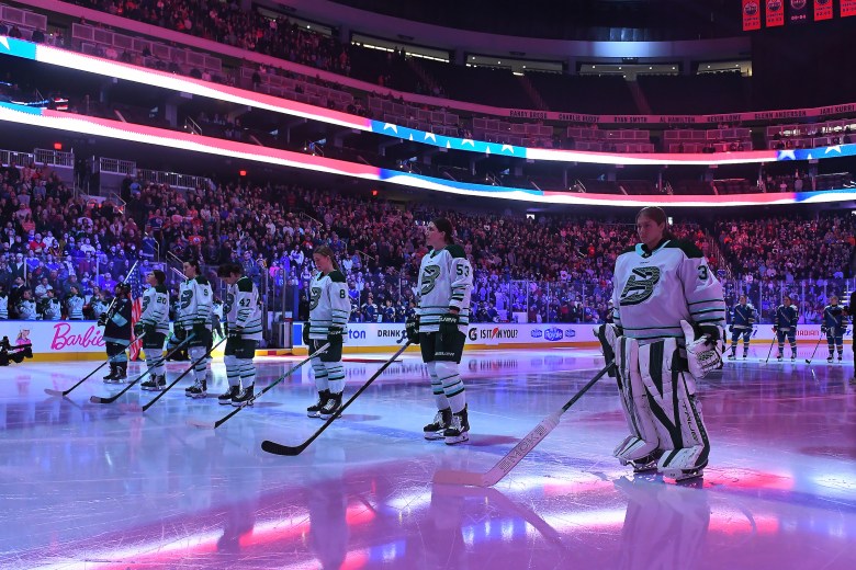 Fleet players stand along the blue line for the national anthem. They are wearing white away uniforms.