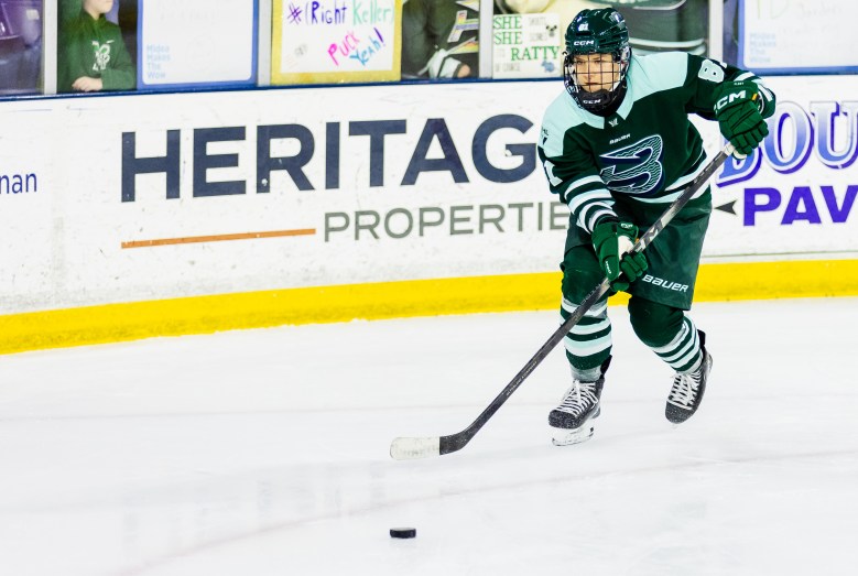 Neubauerová looks up ice as she moves the puck during her Fleet debut. She is wearing a green home uniform.