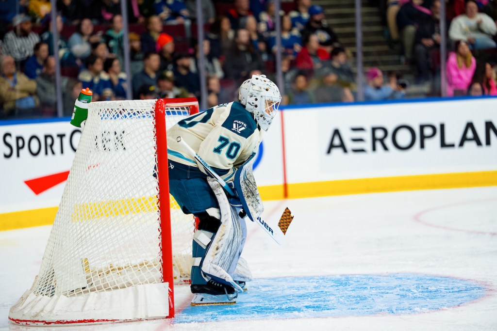 Jackson hunches over as they look up ice. They are wearing a white away uniform.