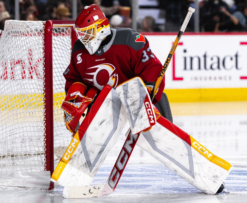 Phillips looks behind her net as she stands ready to make a save. She is wearing a red home uniform.
