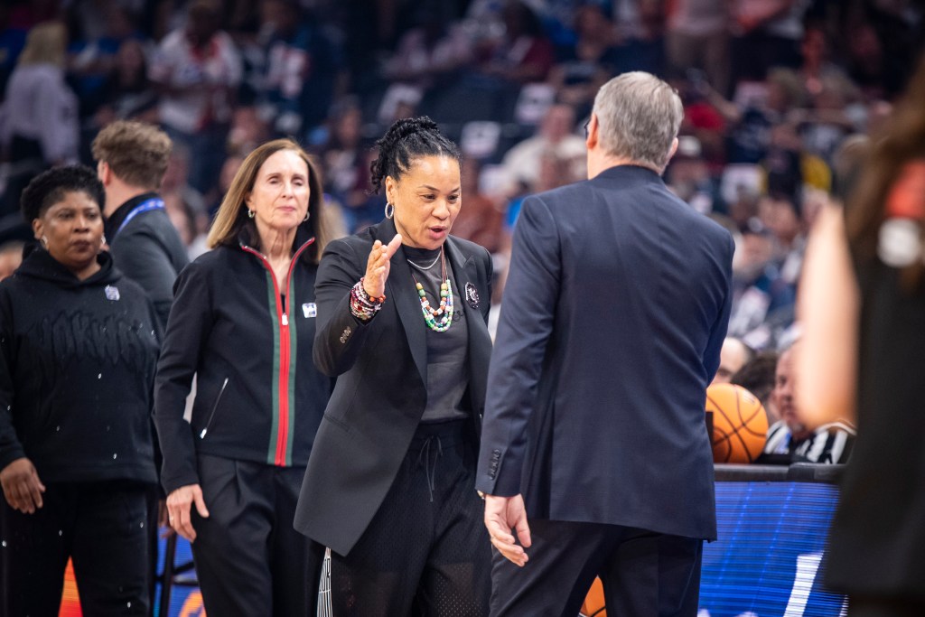 South Carolina head coach Dawn Staley looks at UConn head coach Geno Auriemma and extends her right hand for a pregame handshake. Her staff follows her to shake hands with the UConn staff.