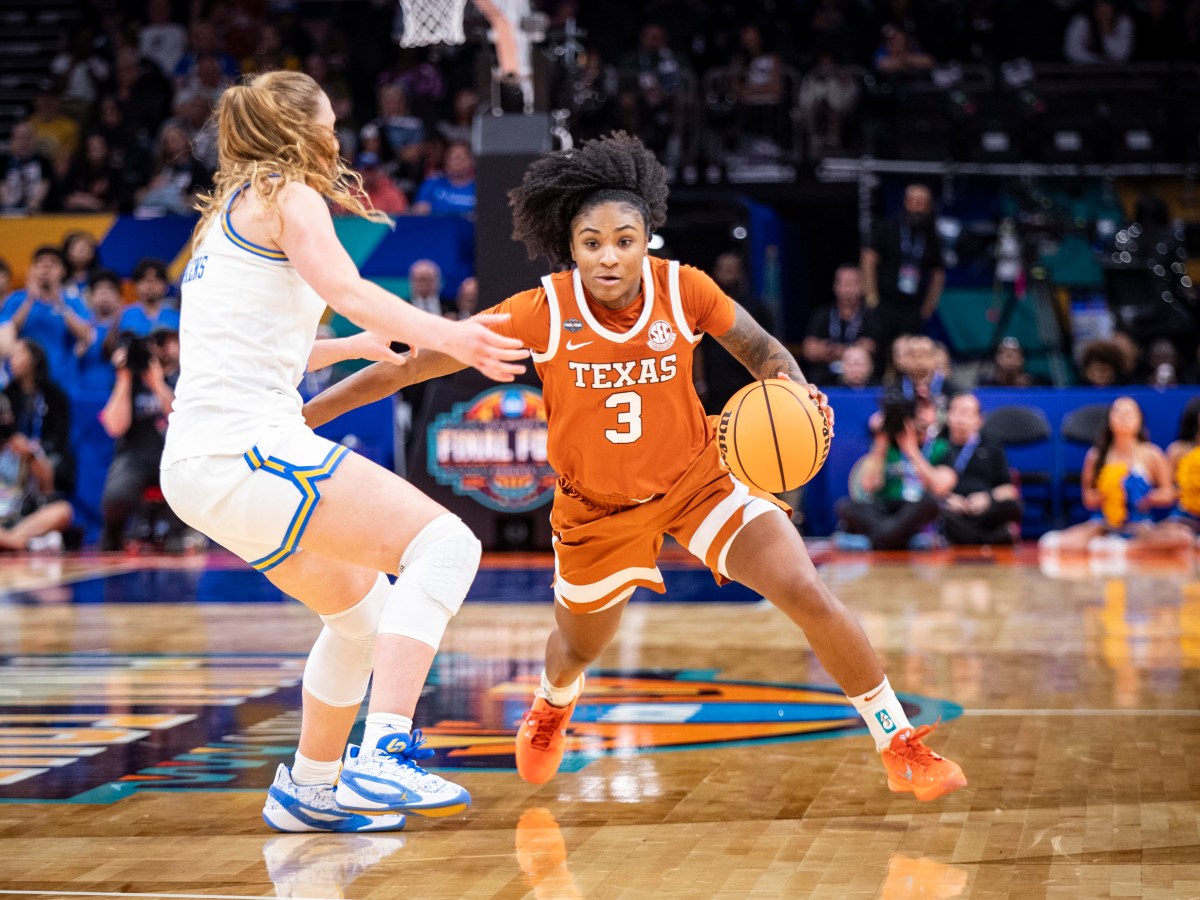 Texas guard Rori Harmon dribbles the ball with her left hand near midcourt. A UCLA defender slides her feet to try to keep Harmon in front of her.