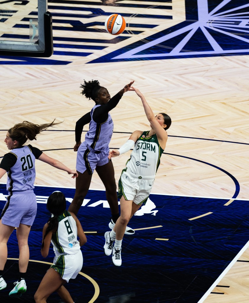 Jade Melbourne falls to her left as she hooks up a shot with her left hand, getting the shot off before the outstretched arm of Leticia Amihere could block it.