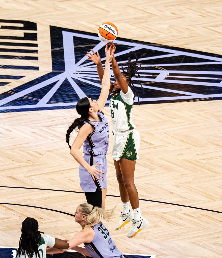 Jaelyn Brown floats a foot in the air as she just barely releases her shot over the Golden State player who looks like she is high-fiving Brown as the ball is just leaving her fingertips.