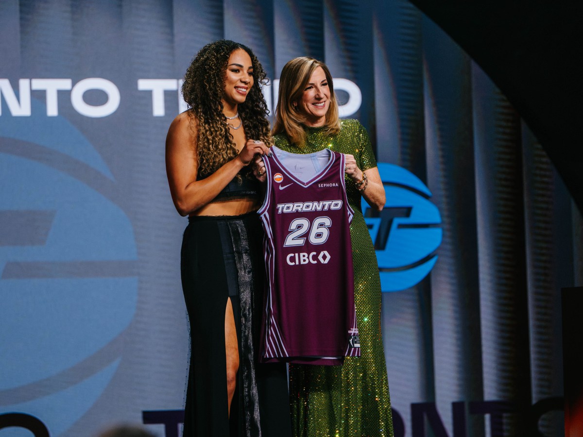 Forward Kiki Rice (left) and WNBA Commissioner Cathy Engelbert (right) pose together on a stage holding Rice's Toronto Tempo jersey between them.
