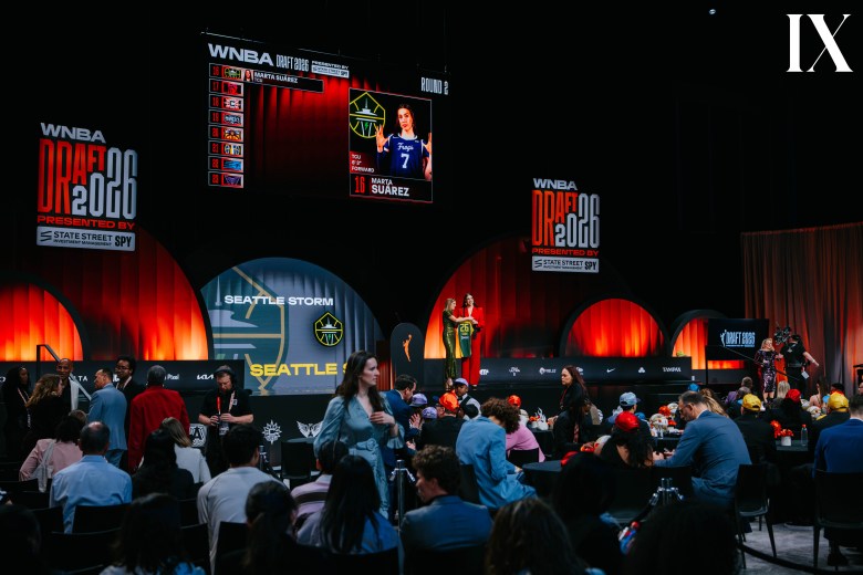Marta Suárez holds up a Seattle Storm jersey with WNBA Commissioner Cathy Engelbert at the 2026 WNBA Draft, while the screens behind her announce her selection.