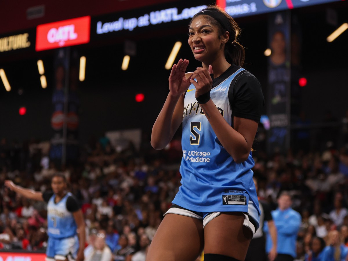 Angel Reese claps her hands and smiles. She is wearing a light blue Chicago Sky jersey.