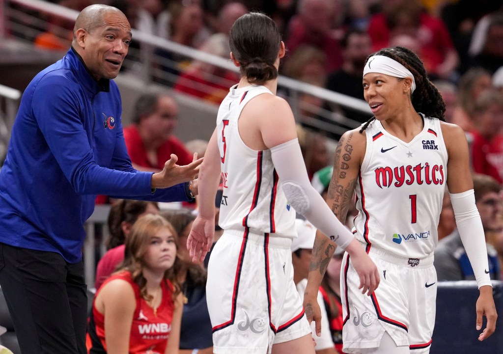 Washington Mystics guards Sug Sutton and Jade Melbourne look at head coach Sydney Johnson as they turn back to the court. Sutton is smiling, and Johnson has an amused expression.