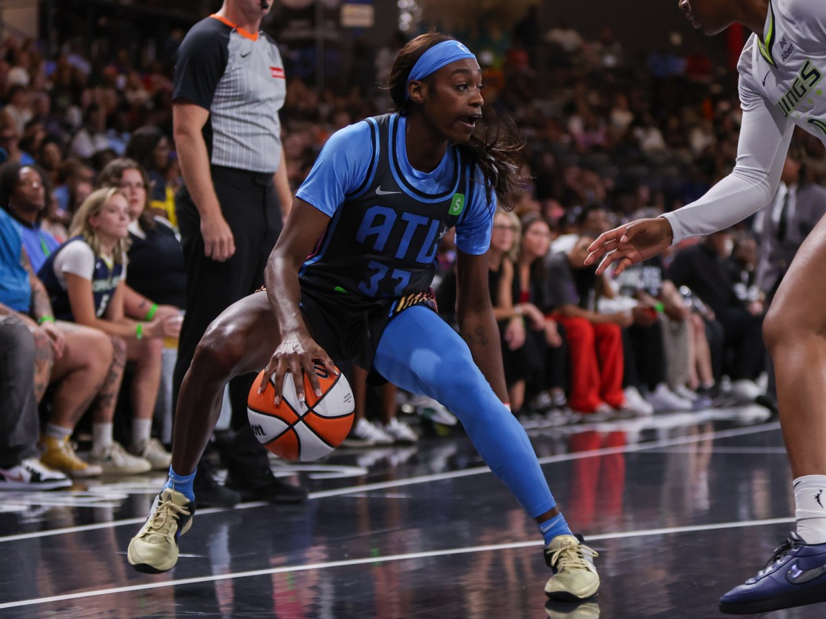 A player in a blue and black uniform guards a basketball on a court