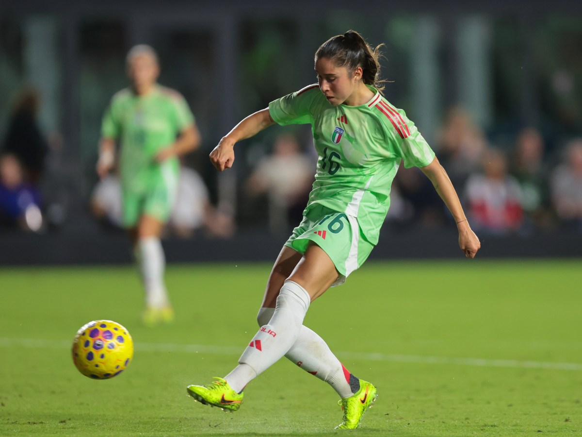 Giulia Dragoni, wearing a light green kit, kicks a yellow soccer ball.