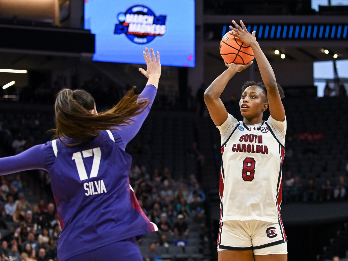 South Carolina forward Joyce Edwards (8) shoots over a defender who has her right hand outstretched. A crowd looks on in the background.