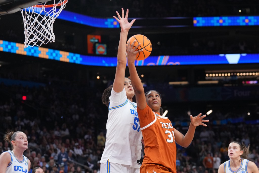 Texas forward Madison Booker grimaces as she tries to shoot a right-handed layup on the left side of the basket over UCLA center Lauren Betts.