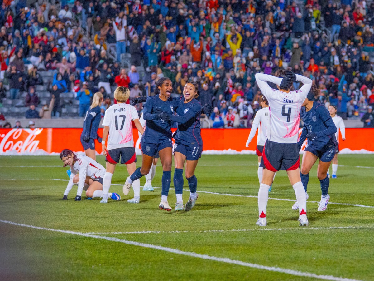 Sophia Wilson and Naomi Girma hug as they run toward the United States' sideline.