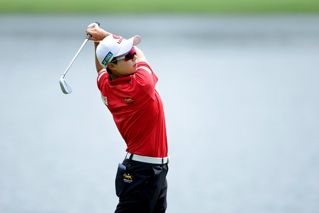 Hyo Joo Kim follows through on an iron shot. Her hands are high up next to her head and she looks toward the shot.