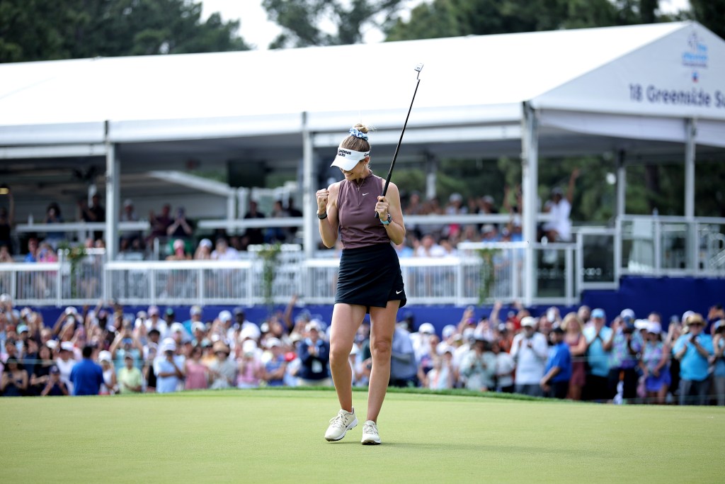 Nelly Korda pulls both of her arms down to L-shapes and fist pumps as she celebrates her win at The Chevron Championship. She's on the green with her putter in her left hand, and the crowd looks on and applauds behind her.