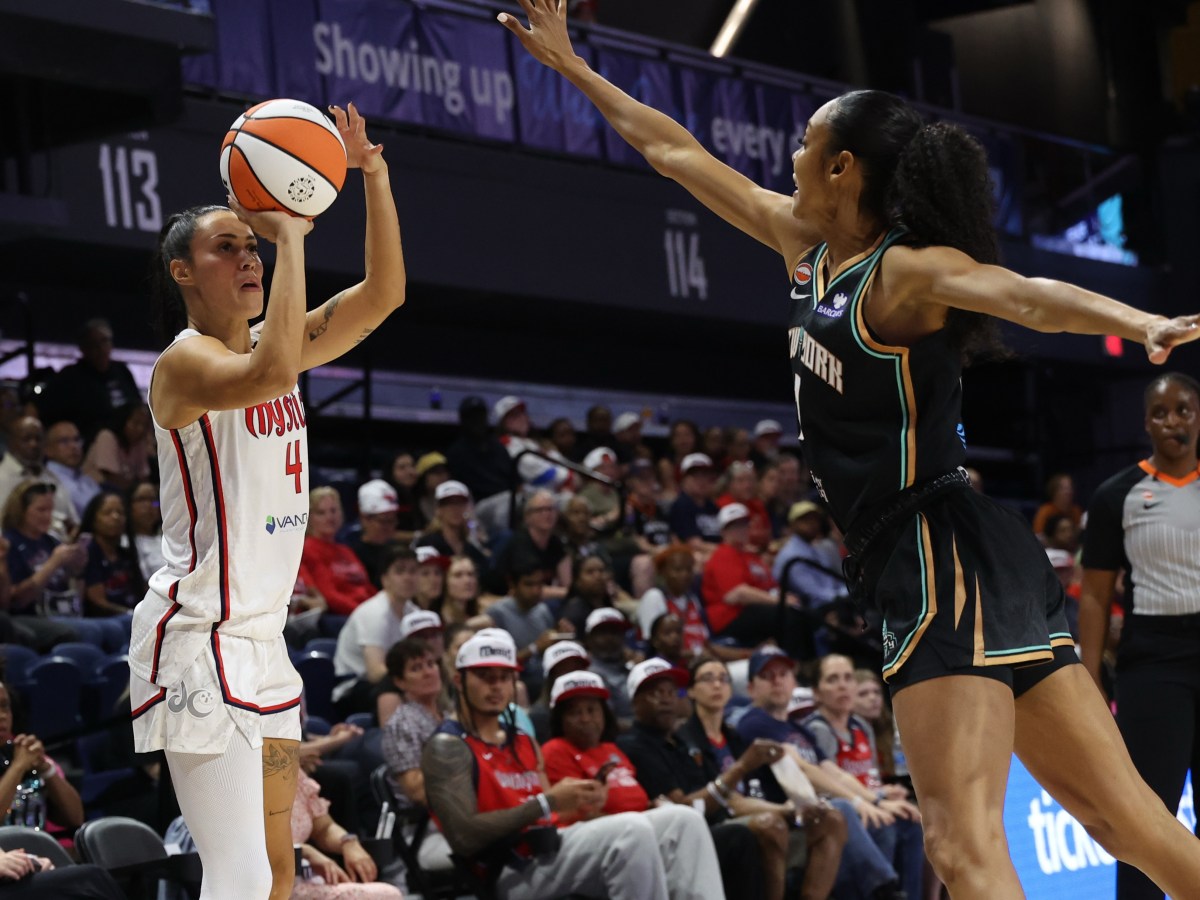 Washington Mystics guard Ally Wilson shoots a right-handed jump shot. New York Liberty guard Rebekah Gardner leans toward her with her right hand up to contest the shot.