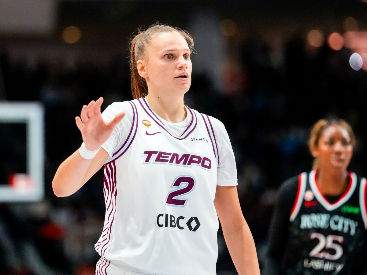 Toronto Tempo player Laura Juskaite on the court in the white jersey with one Portland Fire player in the background.