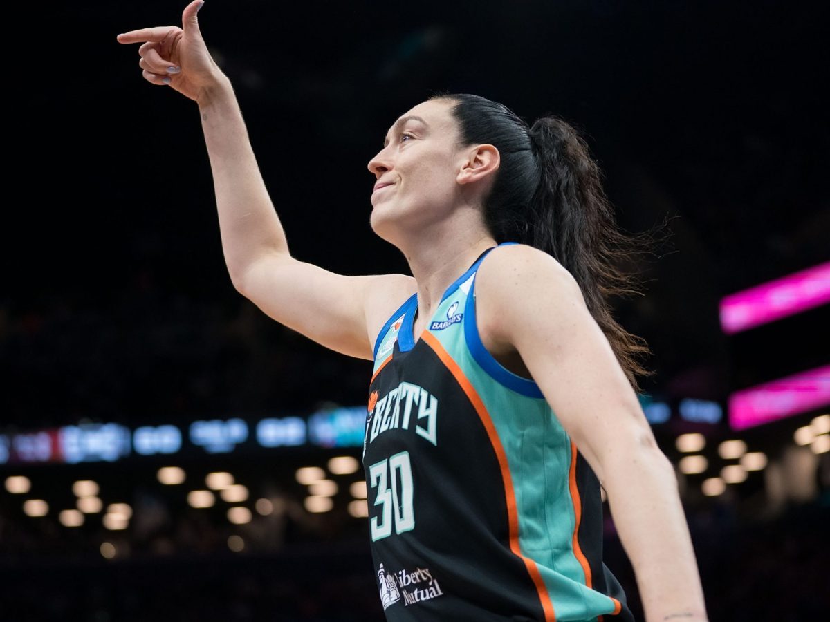 Breanna Stewart reacts to a play on the court by lifting her right arm up with her thumb and index fingers sticking out