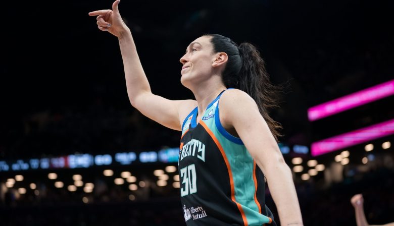 Breanna Stewart reacts to a play on the court by lifting her right arm up with her thumb and index fingers sticking out