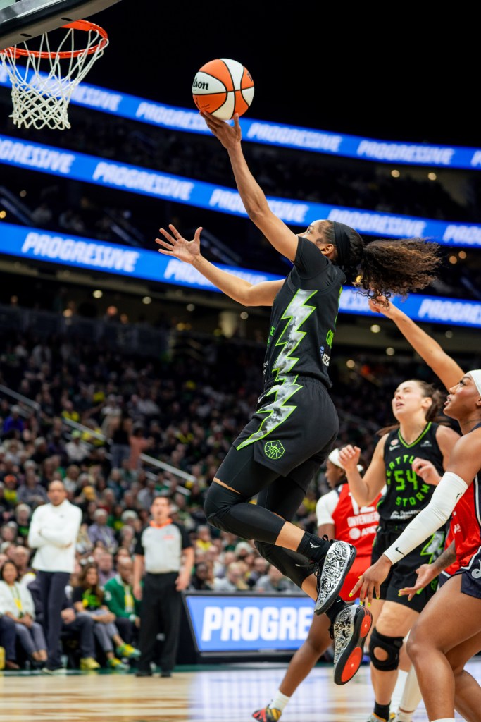Zia Cooke hangs a few feet off the ground as she is about to release her layup shot at the rim with defenders behind her, lost by her quick first step.