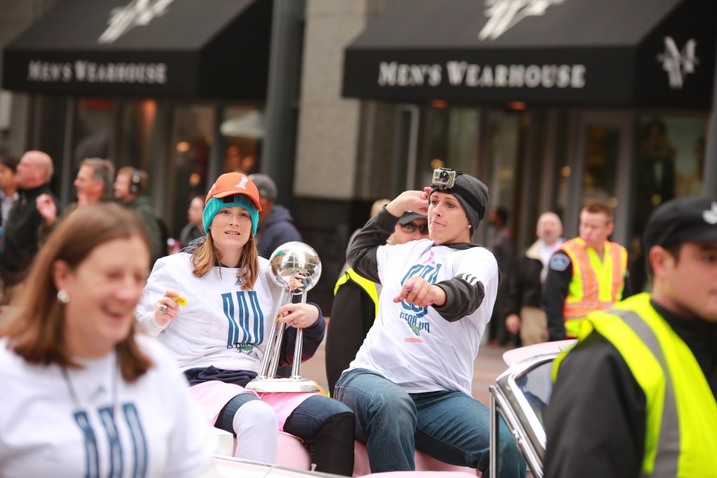 Janel McCarville and Lindsay Whalen ride in a convertible wearing their white championship shirts
