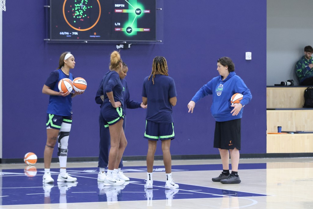 Basketball players gathered in a circle talking about a practice drill