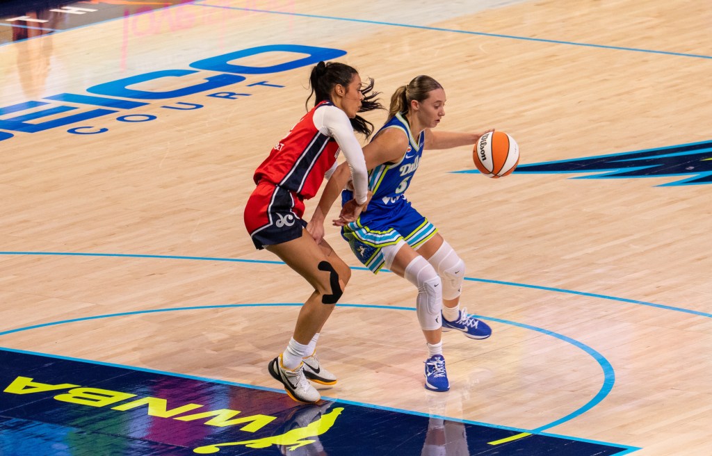 Washington Mystics guard Ally Wilson bodies up Dallas Wings guard Paige Bueckers, who is dribbling with her left hand and her back to Wilson near the free-throw line.