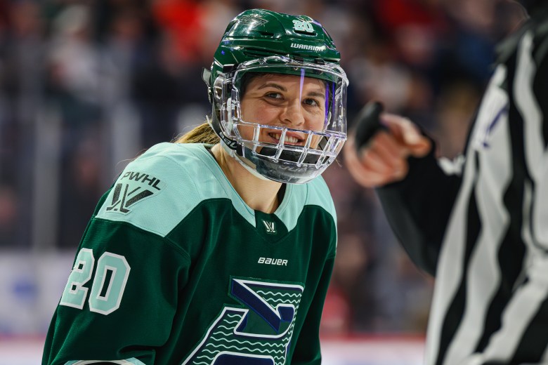Brandt smiles as she prepares for a faceoff. She is wearing a green home uniform.