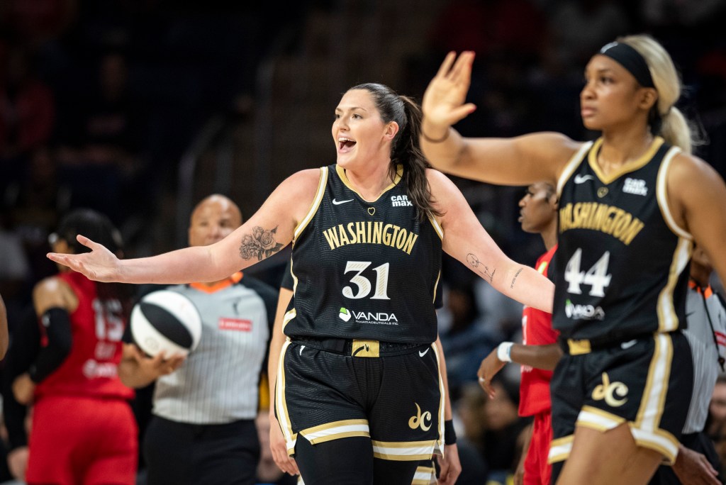 Stefanie Dolson holds her arms out to her sides and makes a confused face, expressing her confusion and frustration as Kiki Iriafen begins to walk in front of her to high-five a teammate.