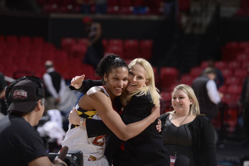 Alyssa Thomas (left) and Brenda Frese shares a celebratory postgame hug as a woman in the background smiles.