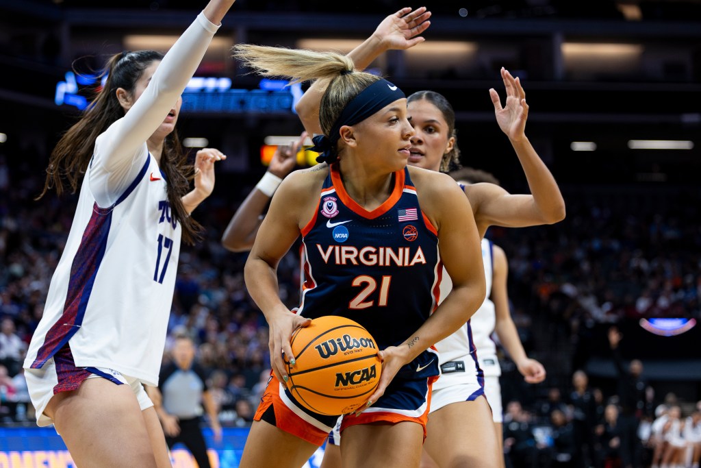 Kymora Johnson holds the ball while being surrounded by a pair of TCU defenders.