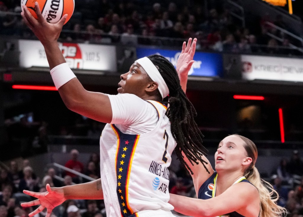 Indiana Fever forward Myisha Hines-Allen is shown from the side shooting a layup. She has gotten past Dallas Wings guard Paige Bueckers and has an open shot with her left hand.
