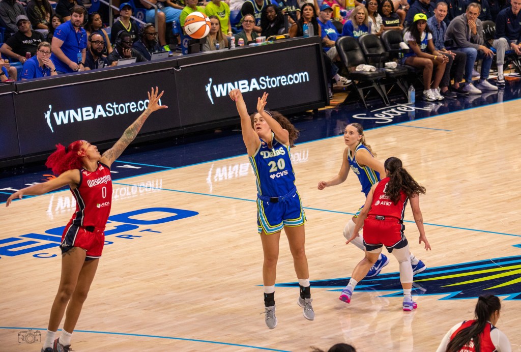 Dallas Wings forward Maddy Siegrist shoots a 3-pointer from the top of the key. A Washington Mystics defender has a hand up but is too far away to contest the shot.