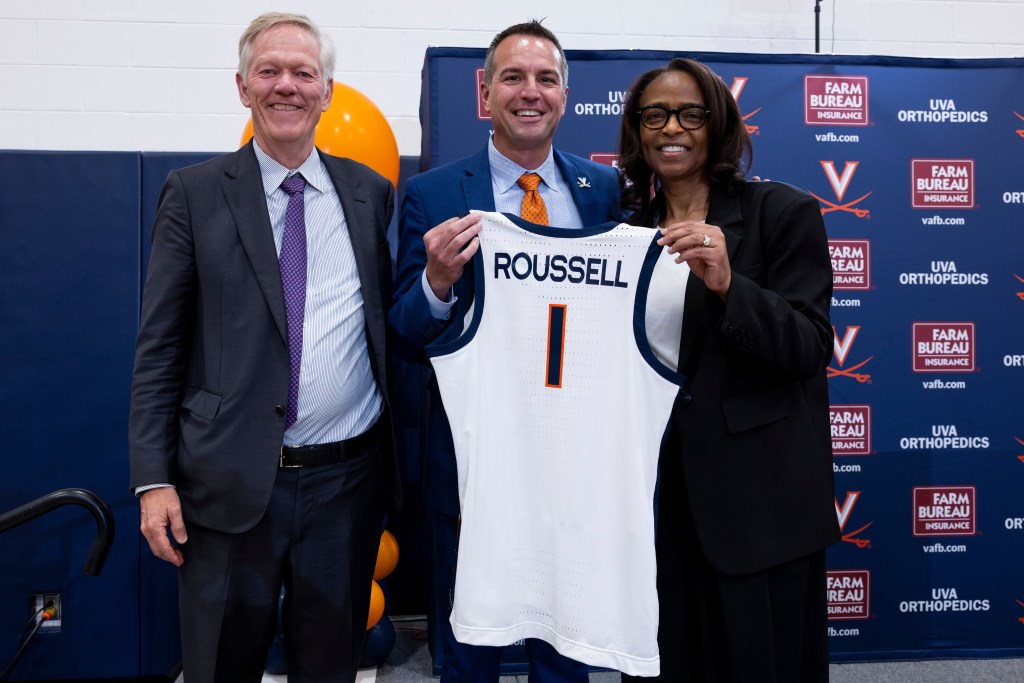 Aaron Roussell holds up a white No. 1 jersey as Dr. Carla Williams also holds the uniform.