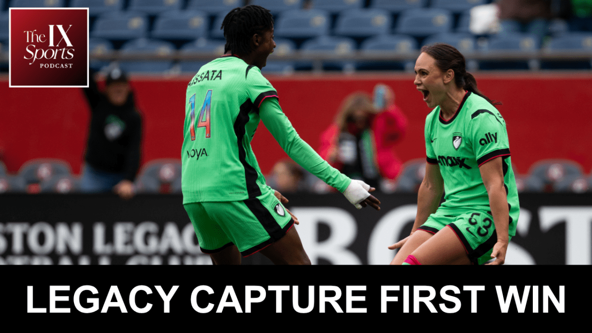 Two women in green soccer kits face each other in celebration.