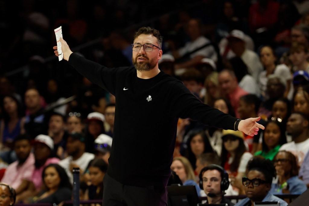 Liberty head coach Chris DeMarco waves a paper in his hand in the air while coaching.