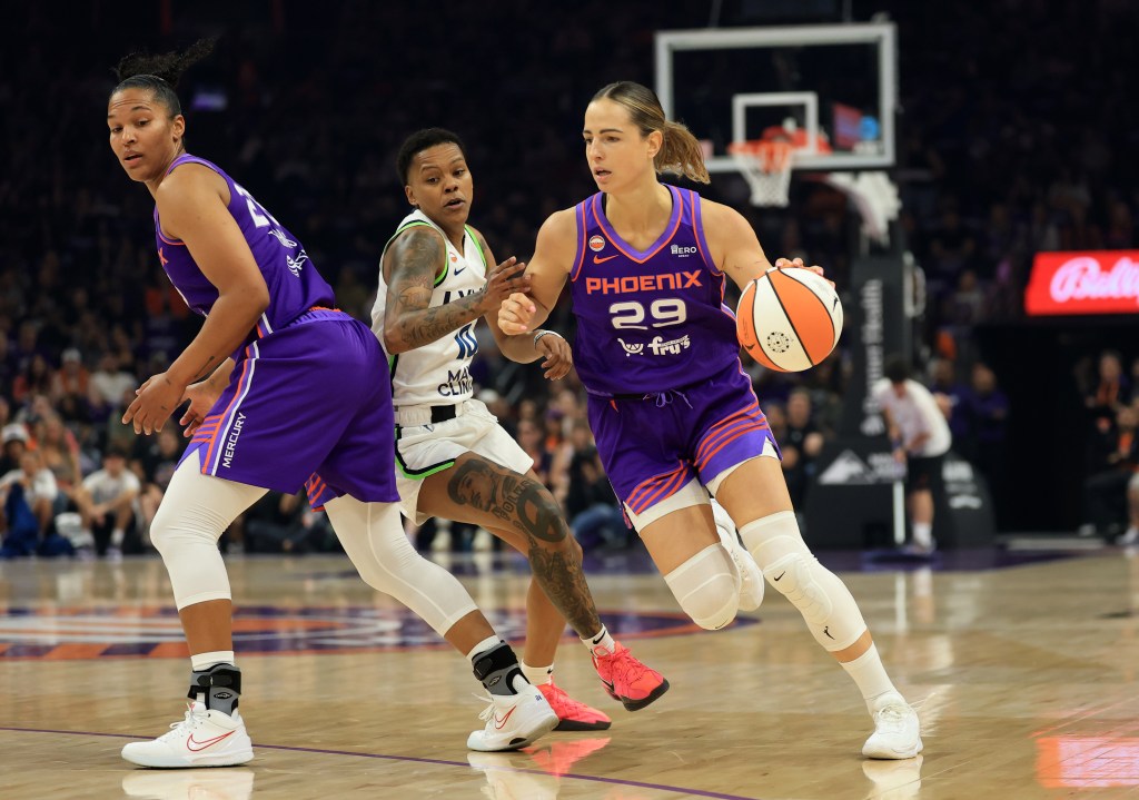 Jovana Nogic and Alyssa Thomas, both in purple Mercury uniforms, run a pick-and-roll with Courtney Williams, in a white Lynx uniform, trying to defend.