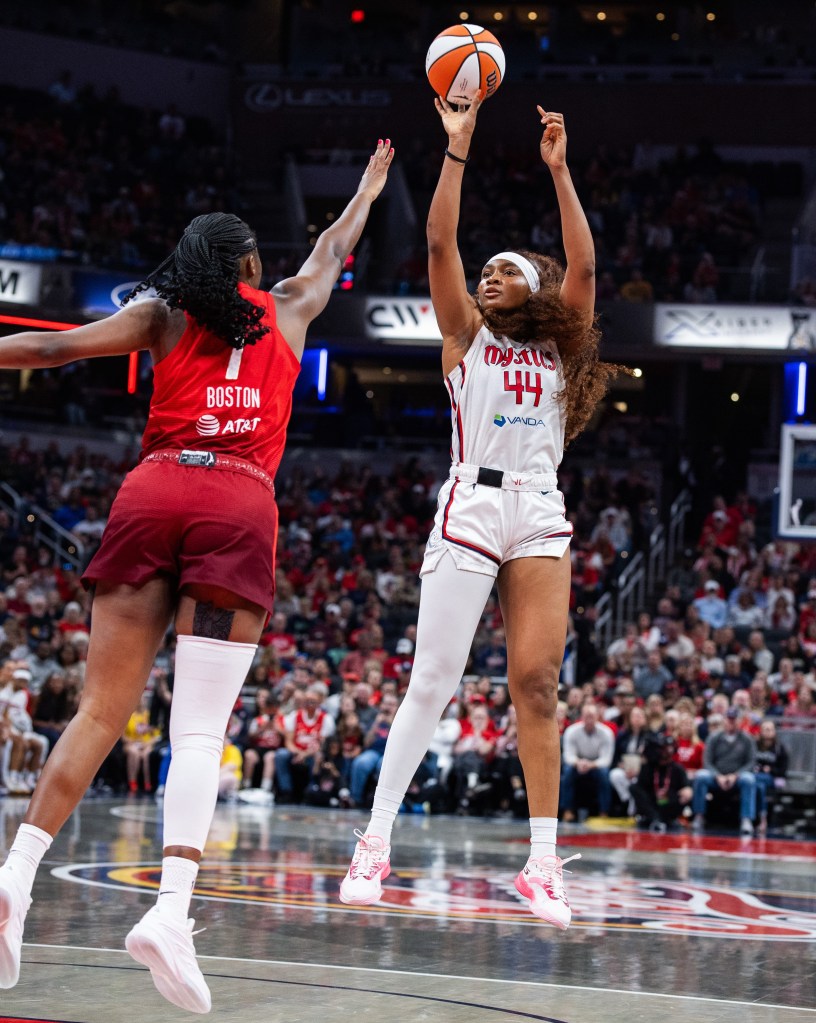 Washington Mystics forward Kiki Iriafen shoots a right-handed jump shot from near the top of the key. Indiana Fever center/forward Aliyah Boston extends her right arm to try to contest the shot.