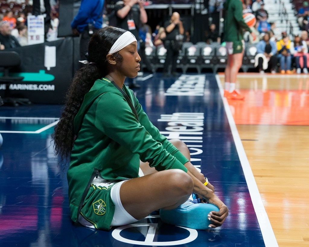 Seattle Storm guard Flau'jae Johnson sits on the baseline with her legs cross, holding her feet still, eyes closed, and meditates ahead of the game.