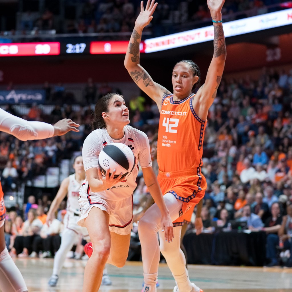Washington Mystics guard Sonia Citron holds the ball underhanded with her right hand and looks up at the basket as Connecticut Sun center Brittney Griner readies to try to block her shot.