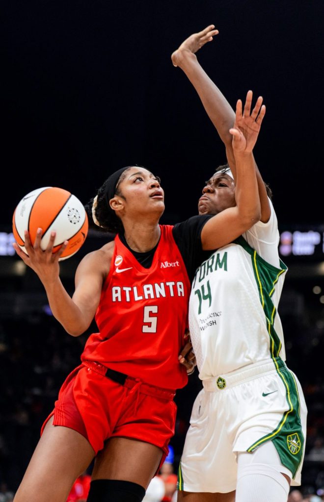 Dominique malonga holds strong against Angel Reese who has one arm up to protect the ball and other going up for a layup, Malonga is connected and has a hand raised ready to make the block.